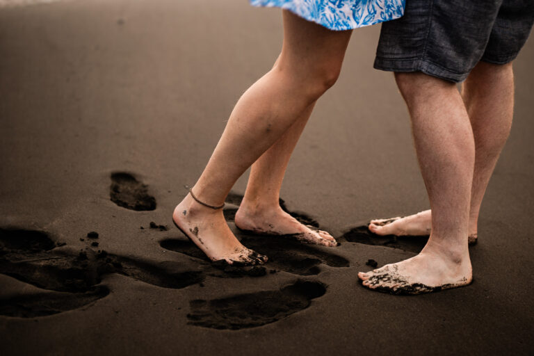 A couple are barefeet on a black sand beach