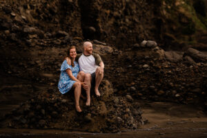A newly engaged couple watch surfers from the rocks at Piha beach