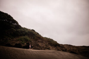 An artistic photography moment where partners explore Piha black sand beach in New Zealand