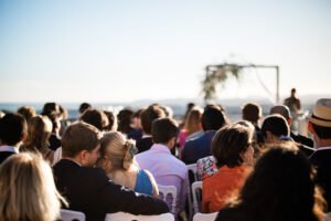 A candid moment between wedding guests during an outdoor wedding ceremony in France