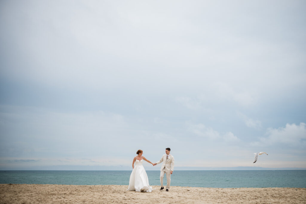 A bride and groom walk together on the beach, during their wedding at Carbis Bay in Cornwall, captured by a wedding photographer UK