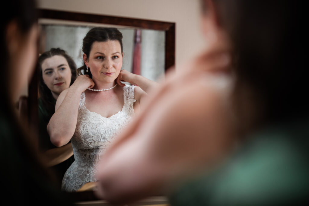 A bride puts on her pearls, before her outdoor wedding ceremony at Davenport House