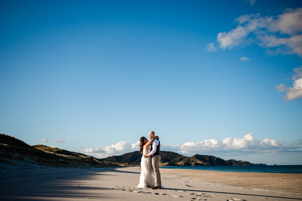 A bride and groom take a quiet moment on the beach, captured by a destination wedding NZ