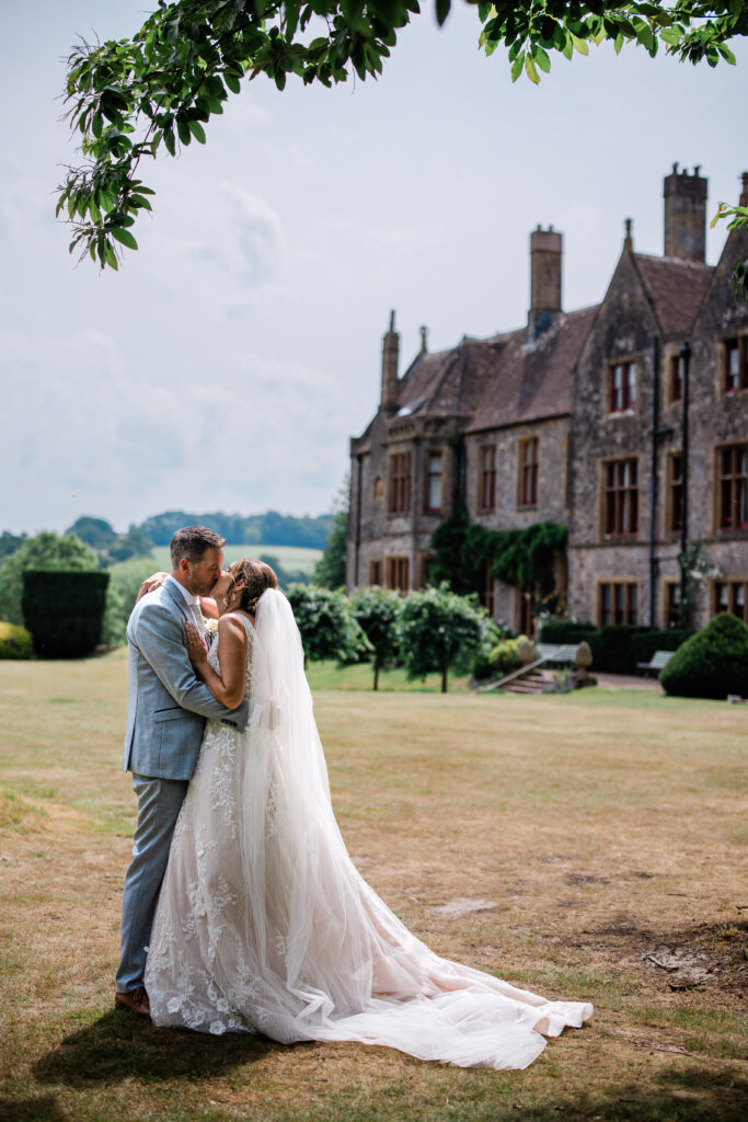 A bride and groom kiss during candid couple photos, at Huntsham Court in Devon