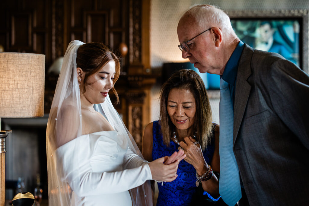 A bride looks at her ring with her parents, during an intimate wedding, during wedding photography UK at Bovey Castle
