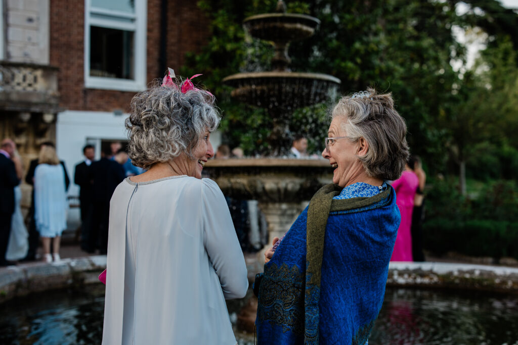 Wedding guests chat during a wedding photographer uk's captures at a Pynes House wedding
