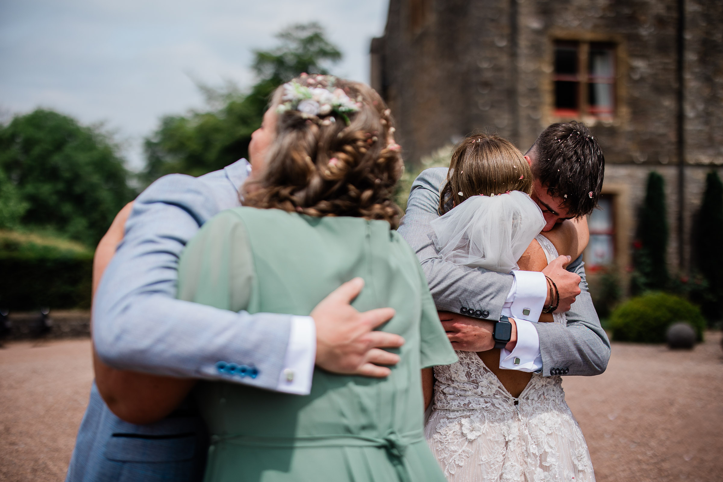 A bride and groom exchange heartfelt hugs with their friends during the wedding reception.