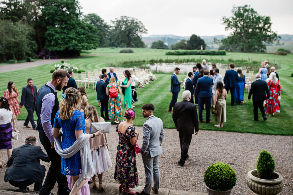 The guests arrive before the ceremony begins, for an outdoor stately home wedding