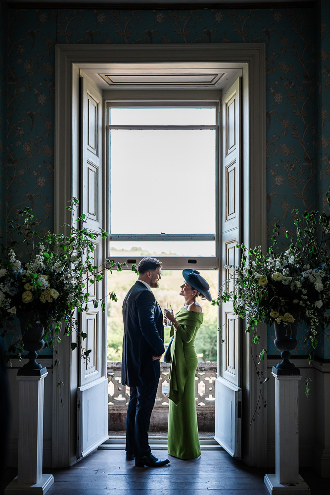 A candid moment between guests during a stately home wedding