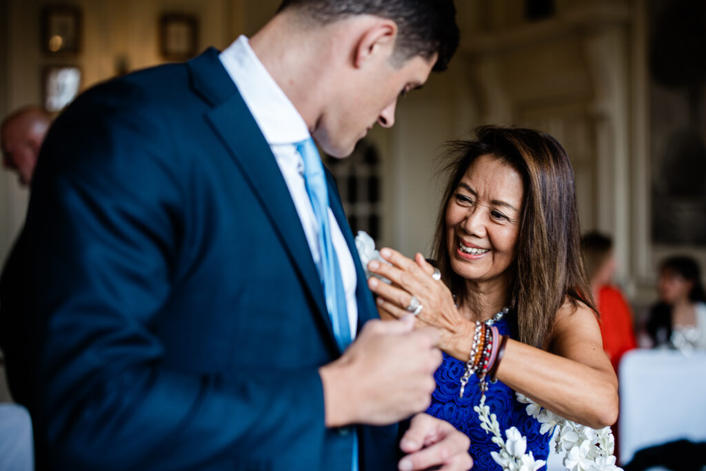 The mother of the groom corrects his buttonhole