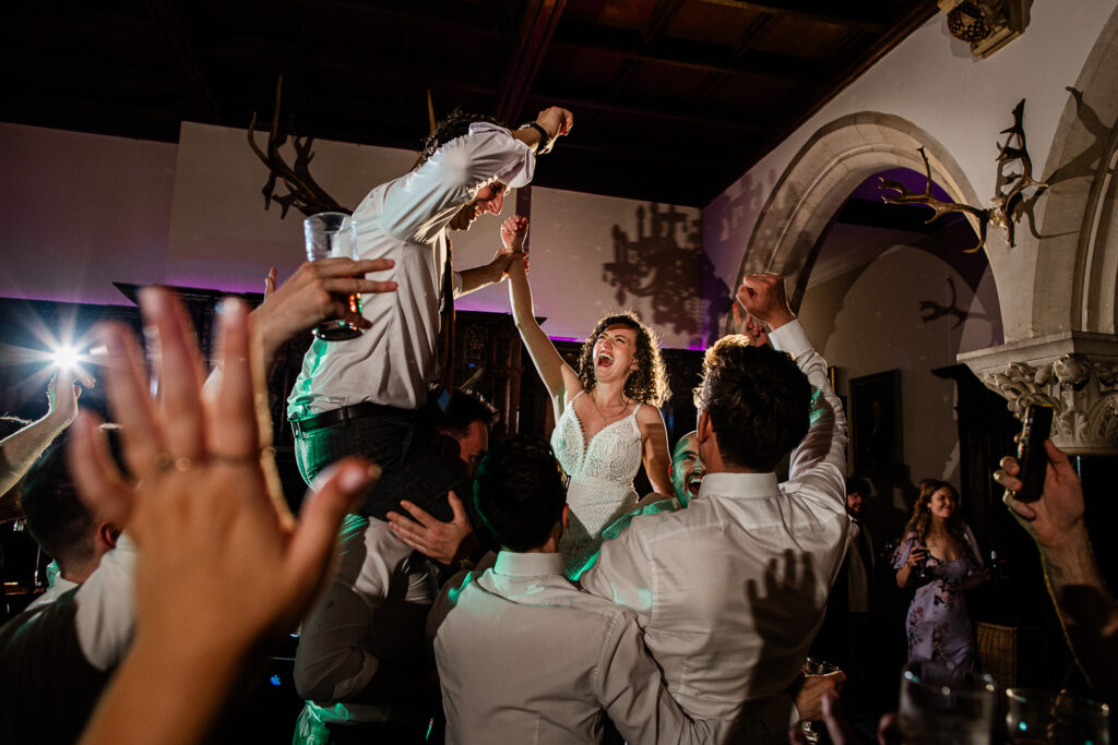 guests carry the bride and groom on their shoulders, on the dance floor