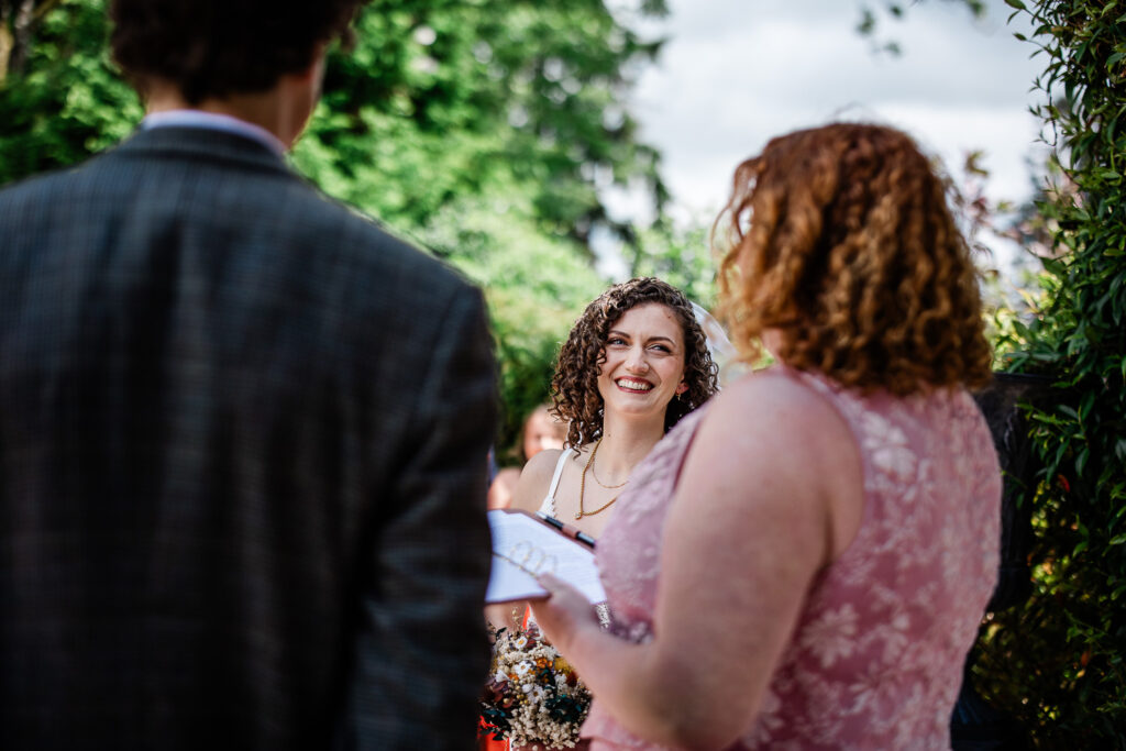 the bride and groom say their vows during an outdoor ceremony at huntsham court