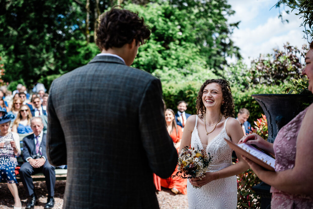 the bride and groom say their vows during an outdoor ceremony at huntsham court