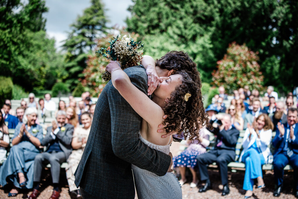 the bride and groom embrace at the end of their wedding ceremony