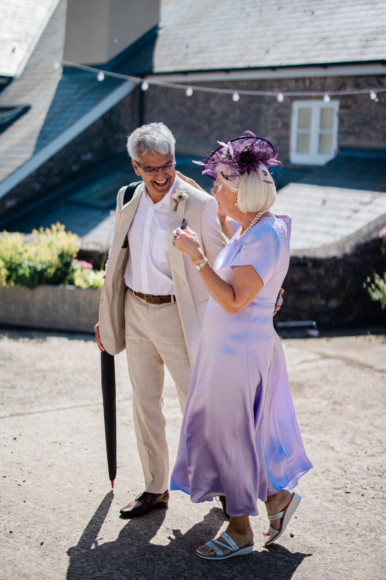 Two wedding guests laughing whilst walking to the wedding ceremony.