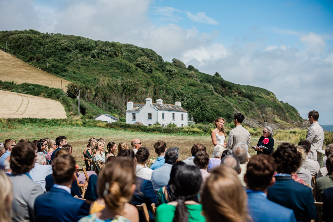 A bride and groom exchange their vows outside, by the sea.