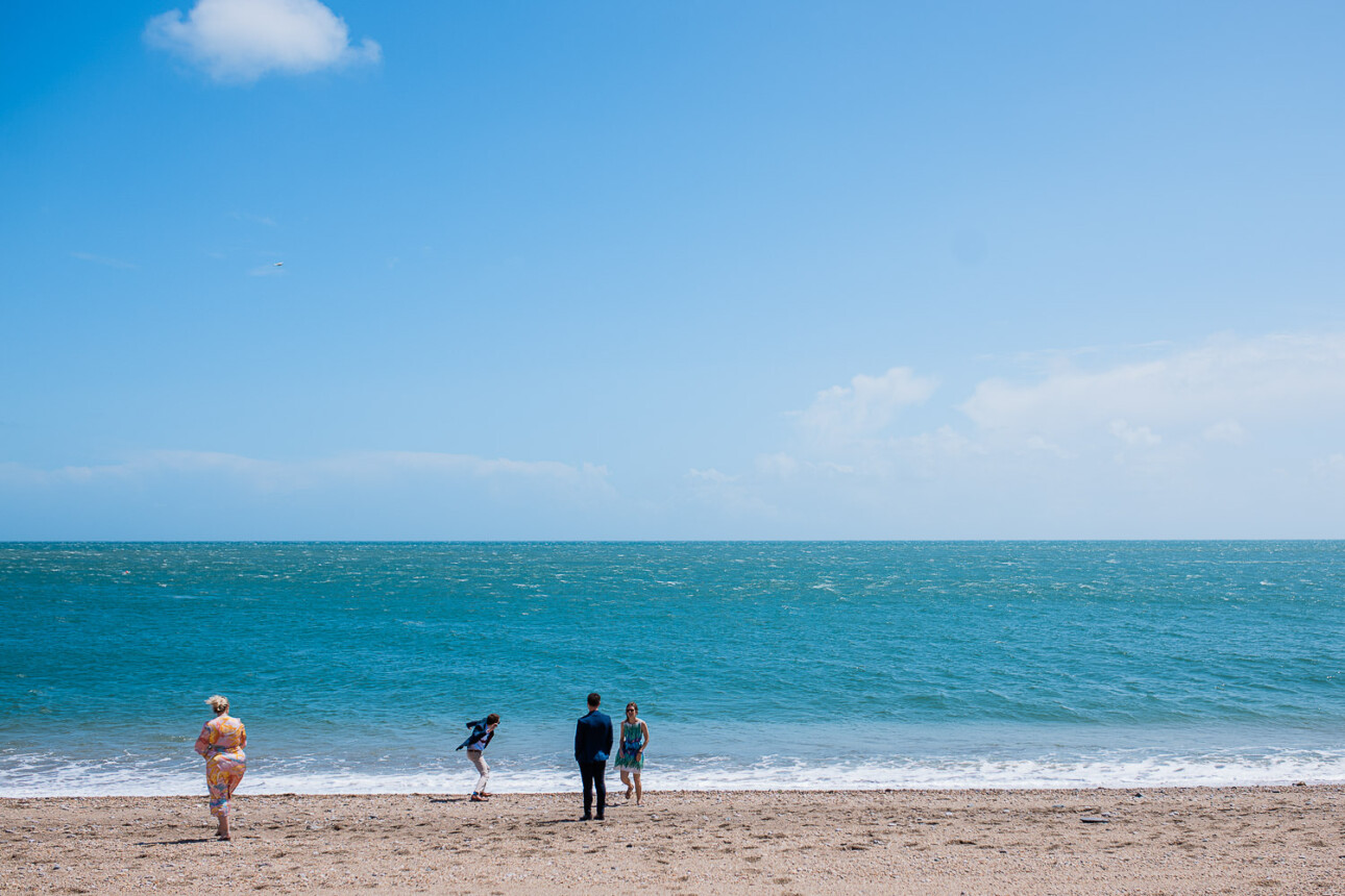 Wedding guests enjoying the beach during seaside wedding reception at The Grain Store in Devon, UK.