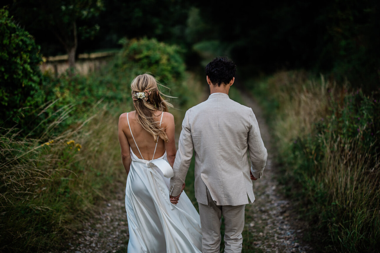 A bride and groom chatting whilst walking down a country lane at Devon wedding venue, The Grain Store Devon.