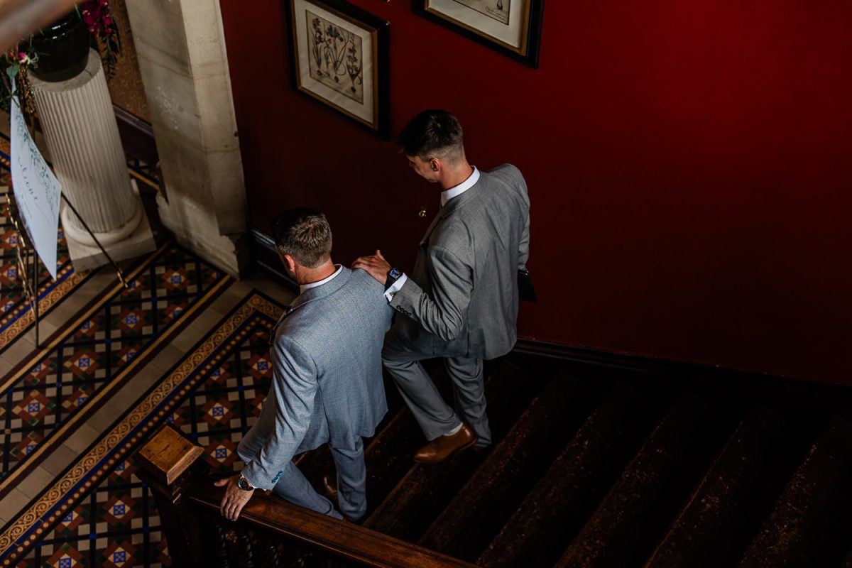 Groom and his son share a tender moment whilst walking down the staircase towards the wedding ceremony at Huntsham Court.