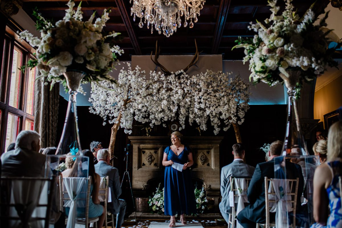 A wedding guest walks down the aisle after saying a wedding ceremony reading, during a Huntsham Court wedding photography session.