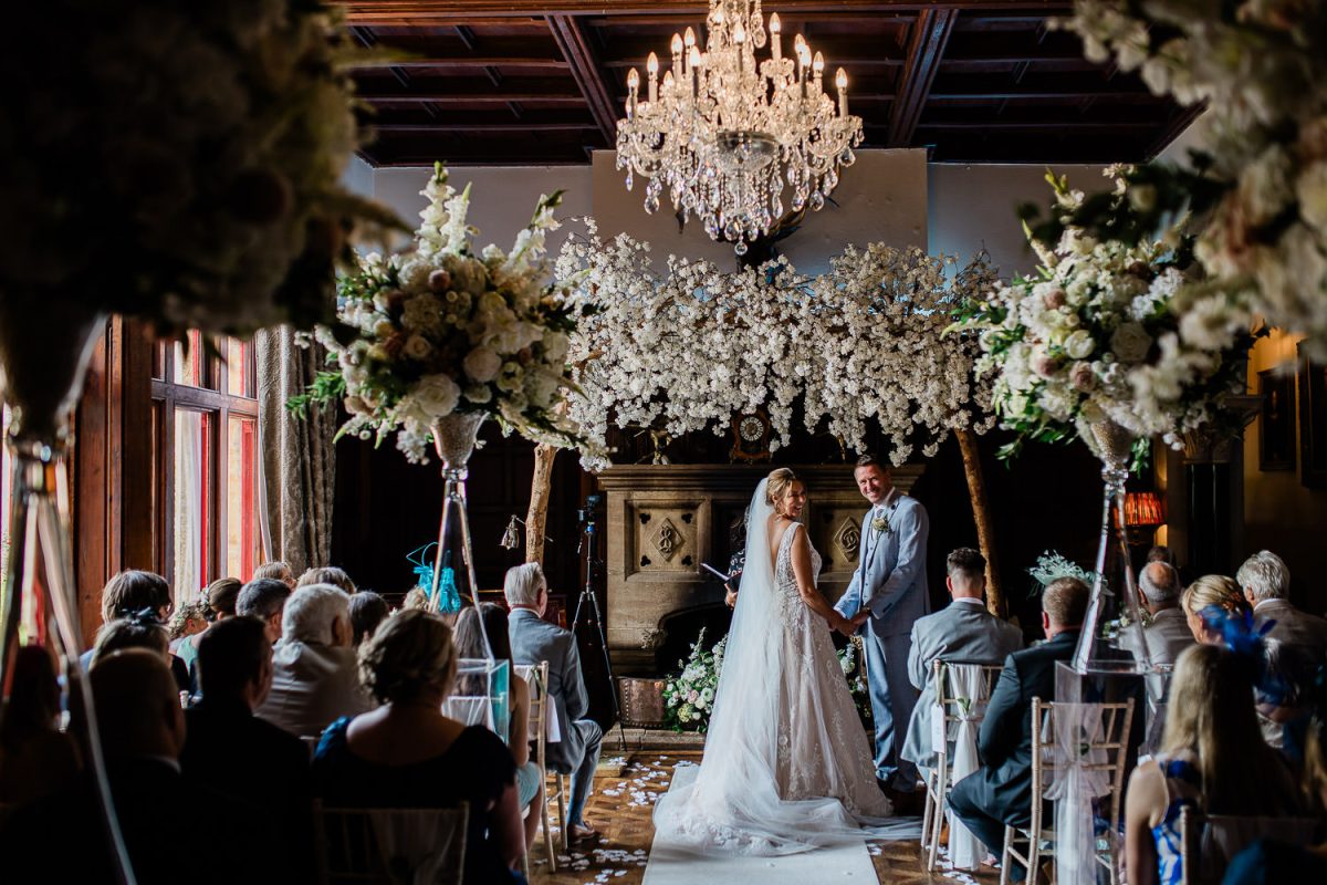 A bride and groom look back laughing, after their friends said a joke during the wedding ceremony at Huntsham Court wedding venue.