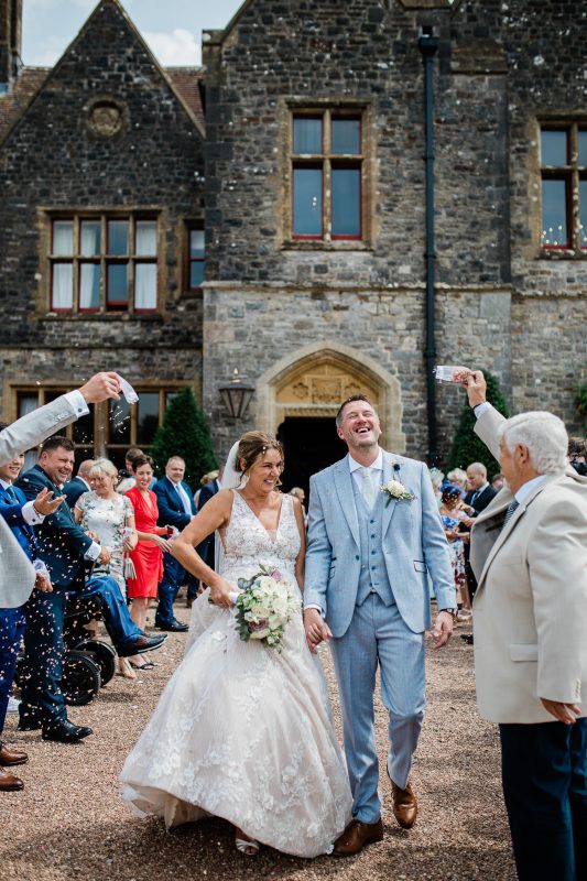 A newly wed couple have confetti thrown on them by guests, during a confetti shot.