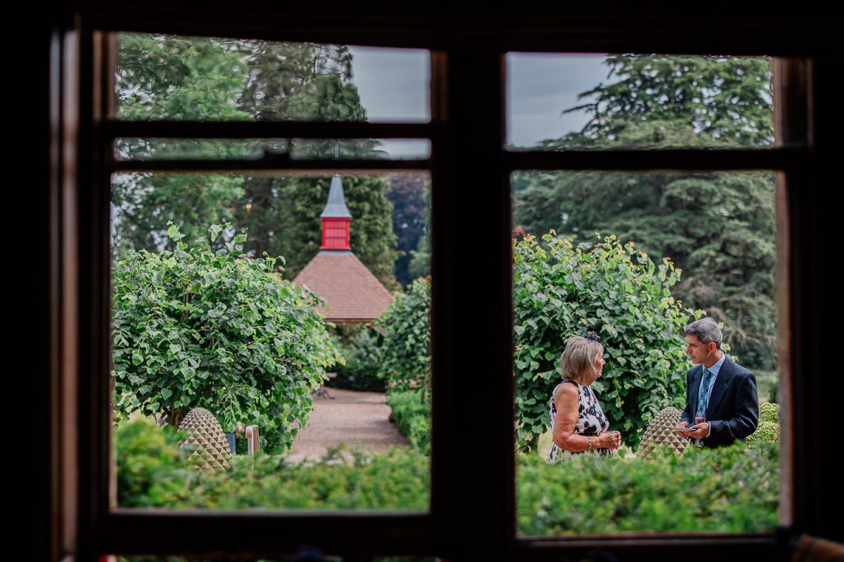 A reportage wedding photography moment of a couple chatting in the gardens of a manor house.