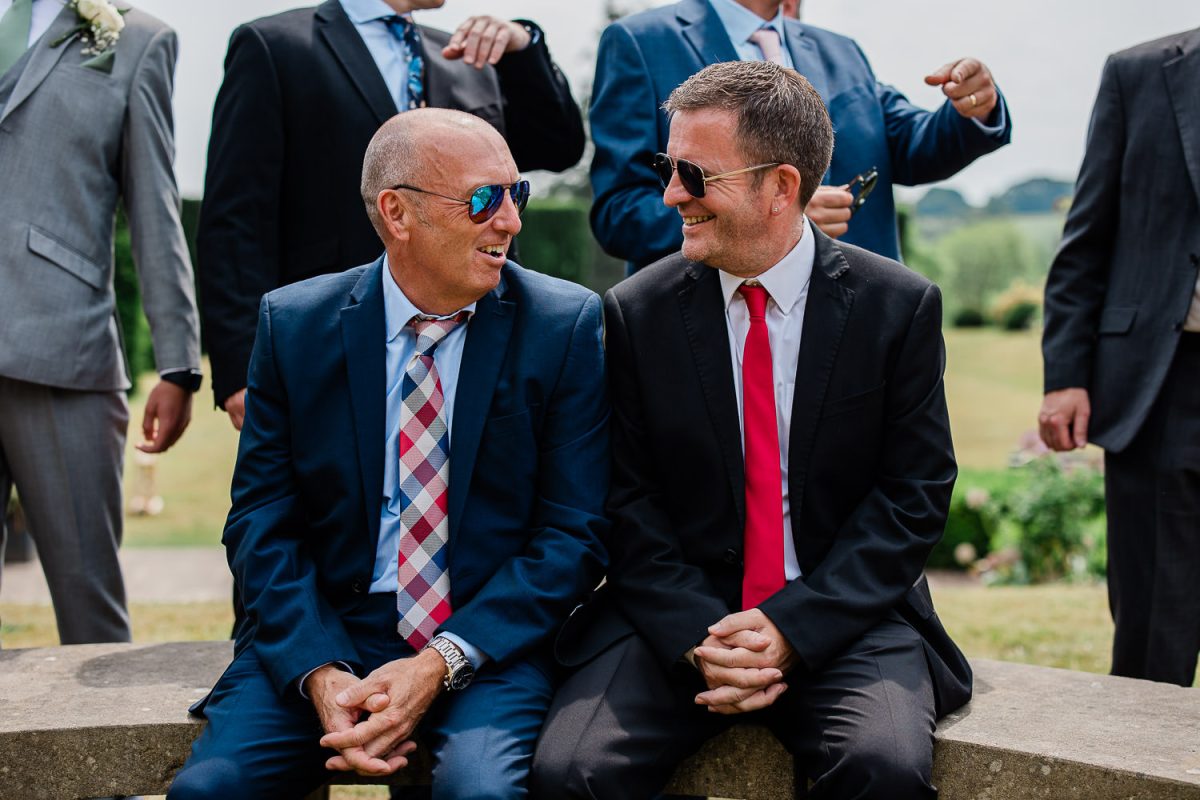 Two wedding guests share a laugh during an English wedding reception.