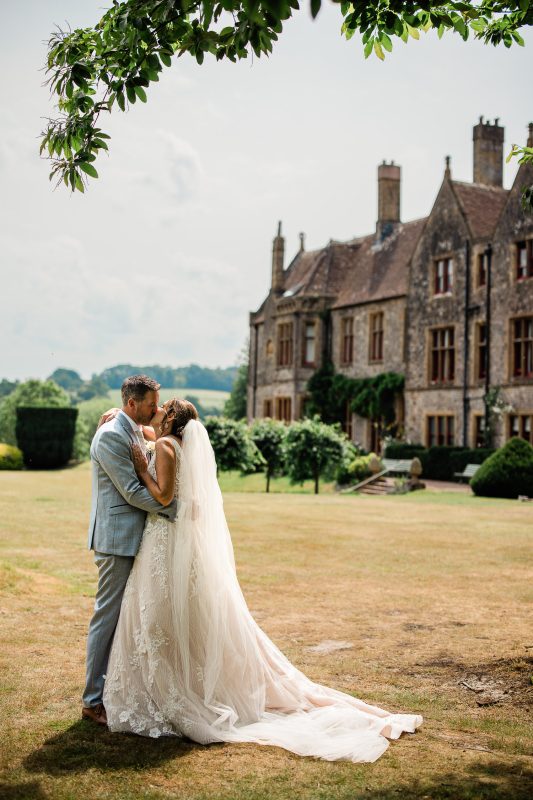 A groom and bride exchange a kiss during a wedding portrait session by Huntsham Court wedding photographer.