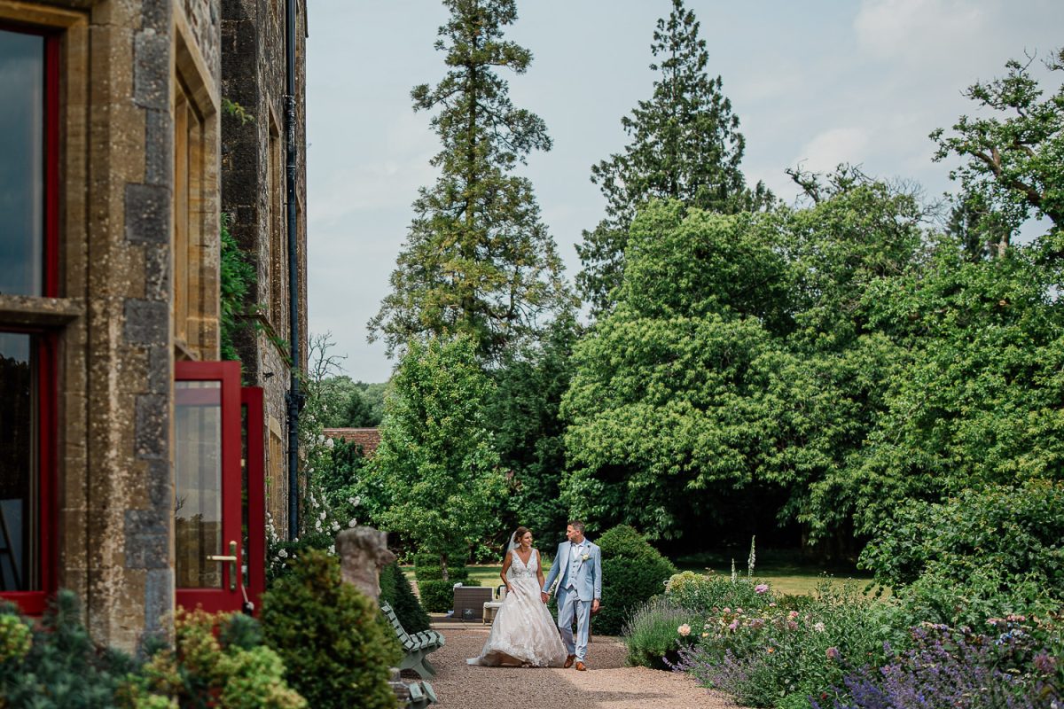 A newly married couple stroll through the grounds of Devon wedding venue Huntsham Court.