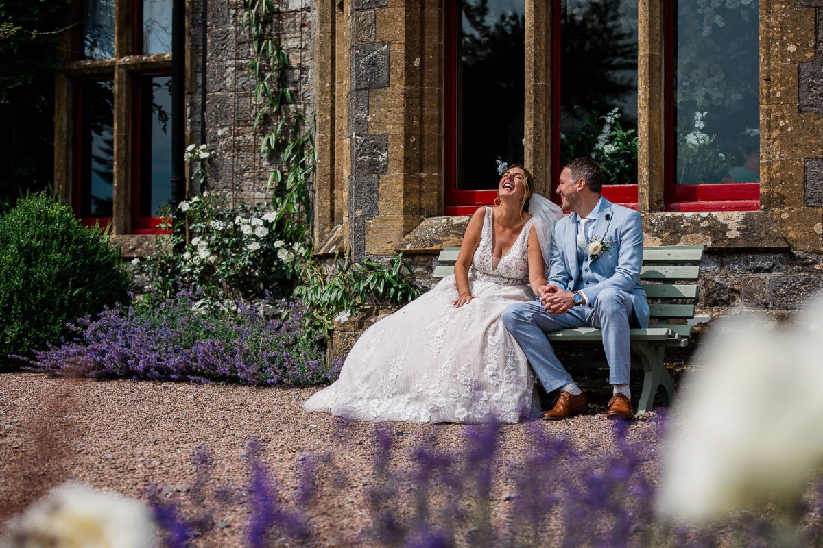 A candid Huntsham Court wedding photography moment of a bride laughing with the groom, at a Tudor style wedding venue in Devon.