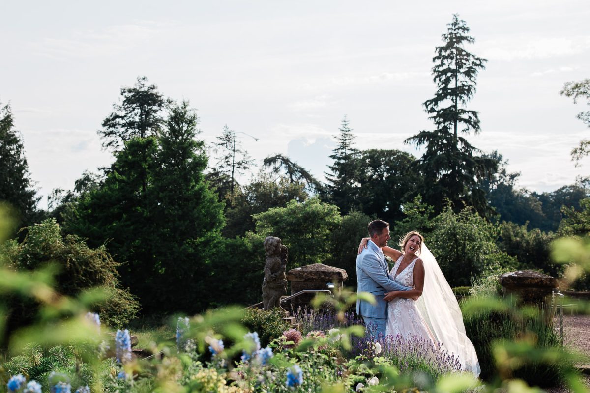 A newly married couple exchange conversation during golden hour in English manor house gardens.