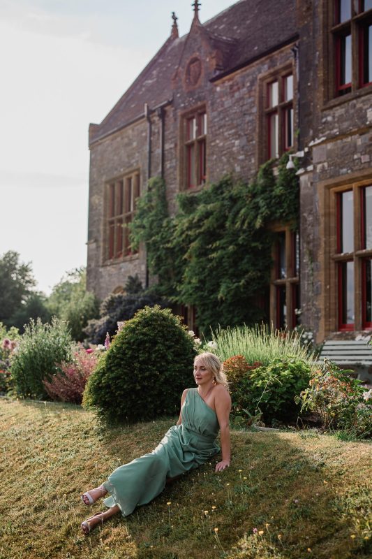 A bridesmaid relaxes in the evening sun, at Huntsham Court in Devon.