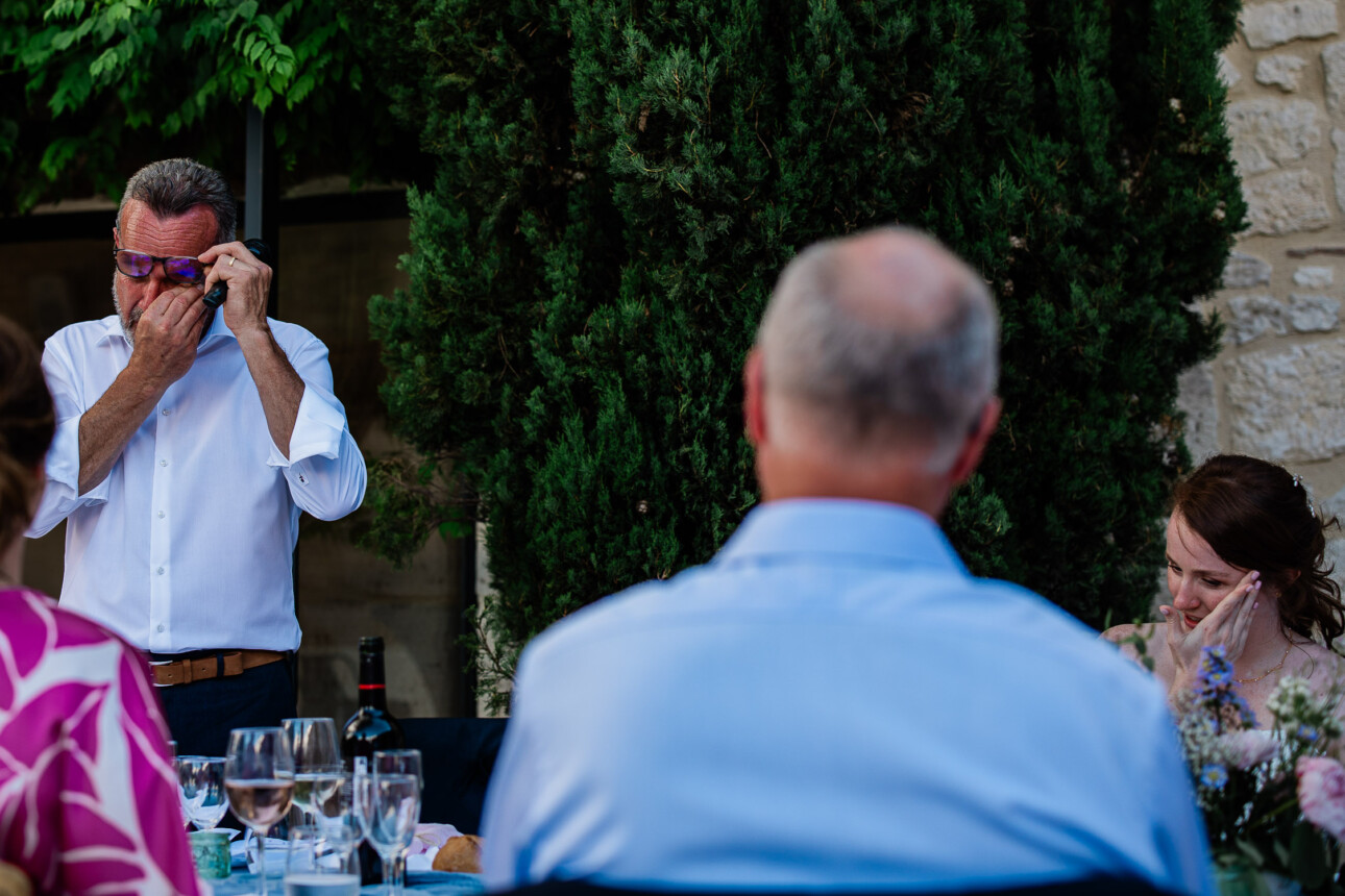 An emotional moment during wedding speeches, where the bride and father of the bride both wipe their eyes.