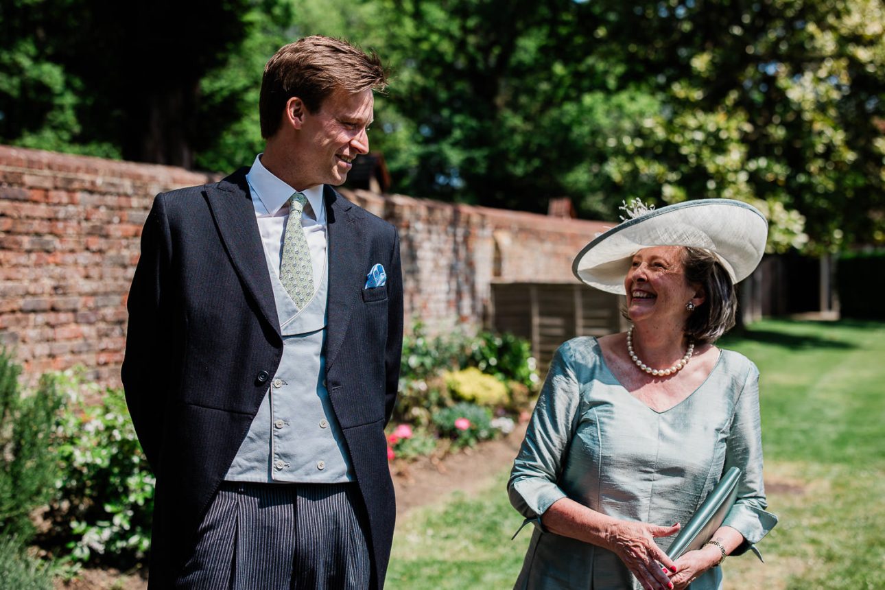 A mother of the groom and usher exchange excited conversation before the wedding ceremony.