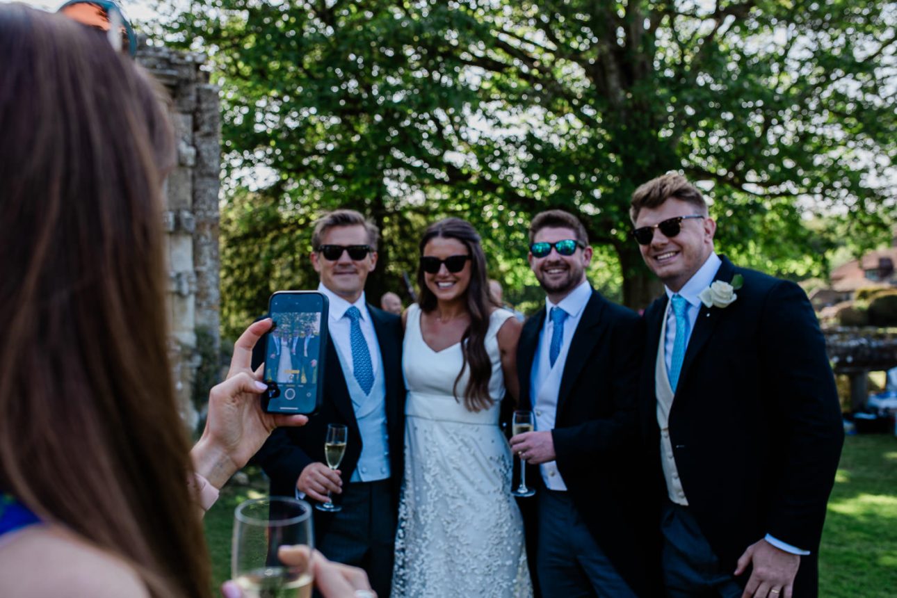 A guest takes a photo of other wedding guests, during an open air reception in England.