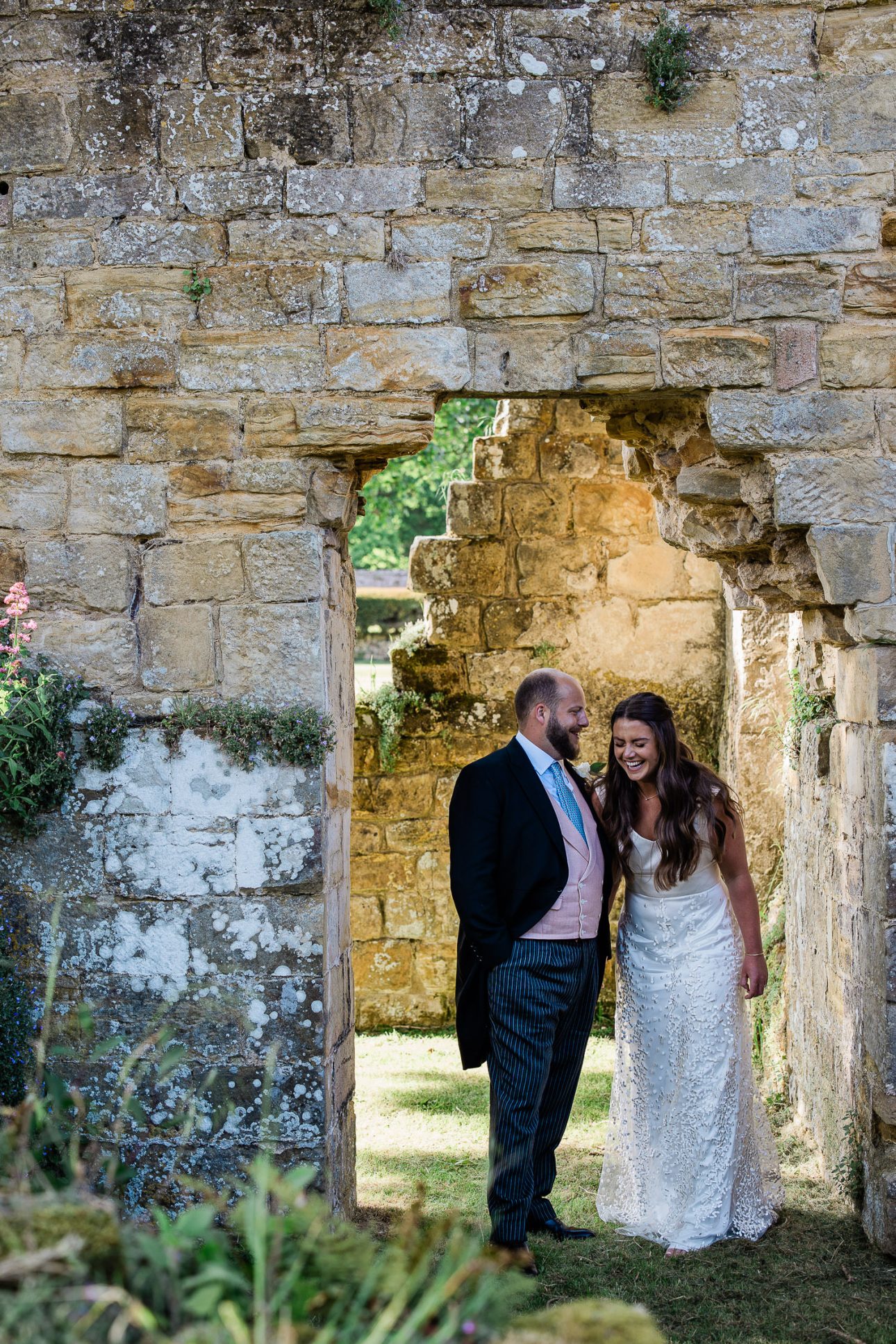 A bride and groom laugh together, during a couple shoot at a historic venue in Sussex.
