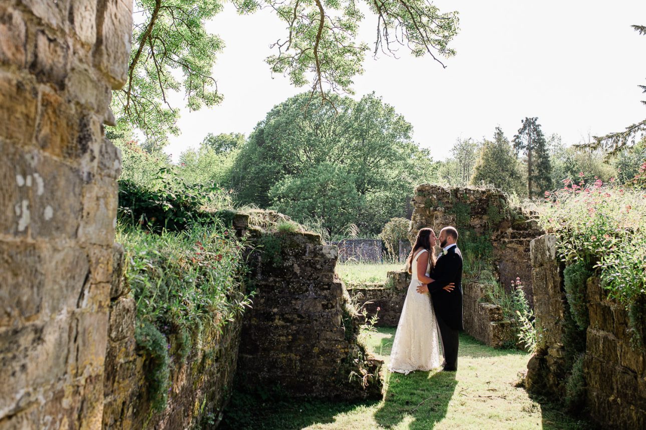 A bride and groom exchange a kiss during golden hour, at a wedding portrait session in West Sussex, UK.