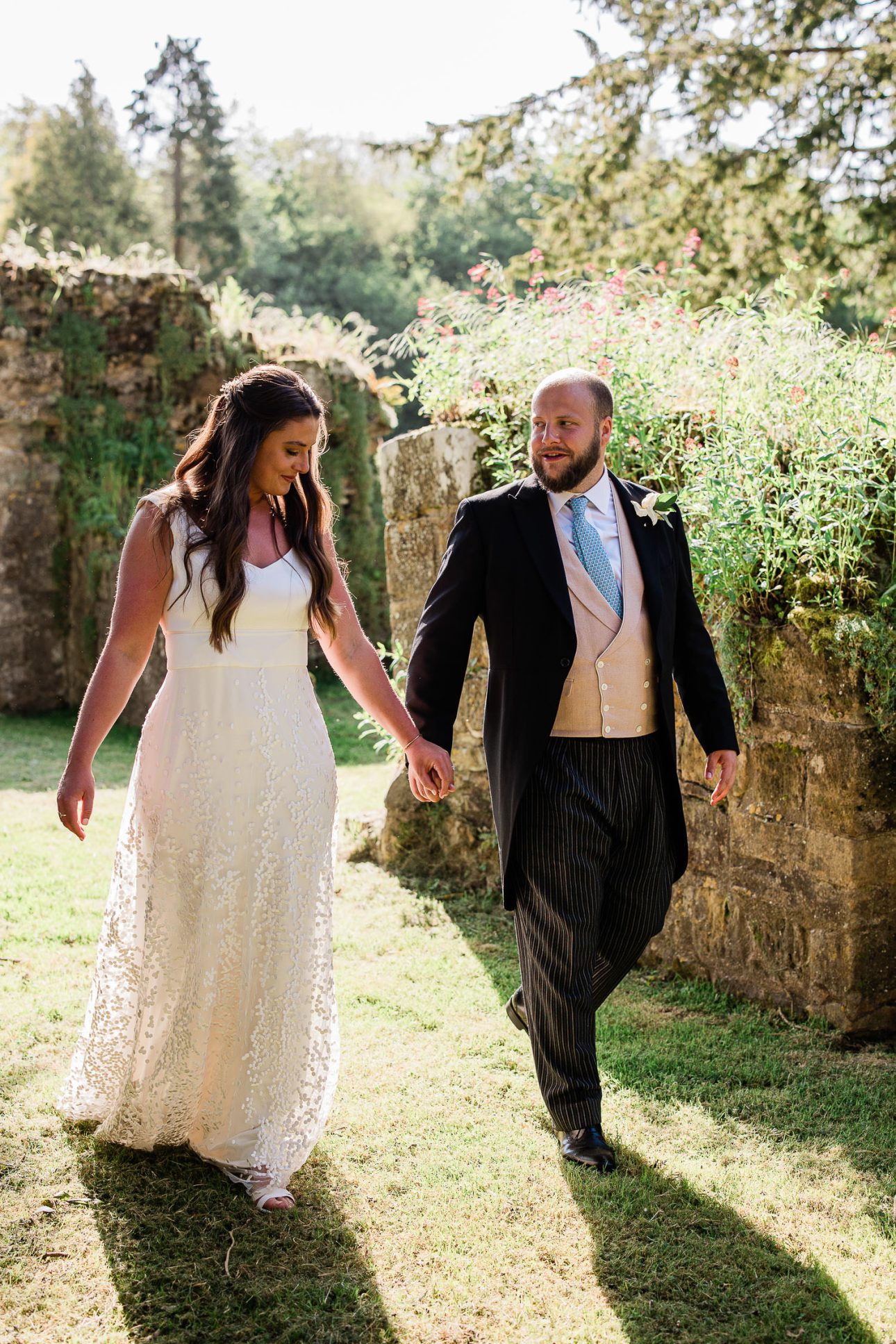 A newly wed couple walk through the English gardens at Slaugham Place, during a couples portrait session by Laura Rosemary Photograpy.