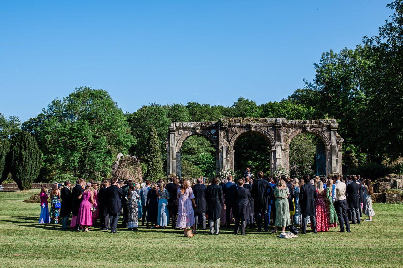 Guests gather around historic arches to listen to open air wedding speeches.