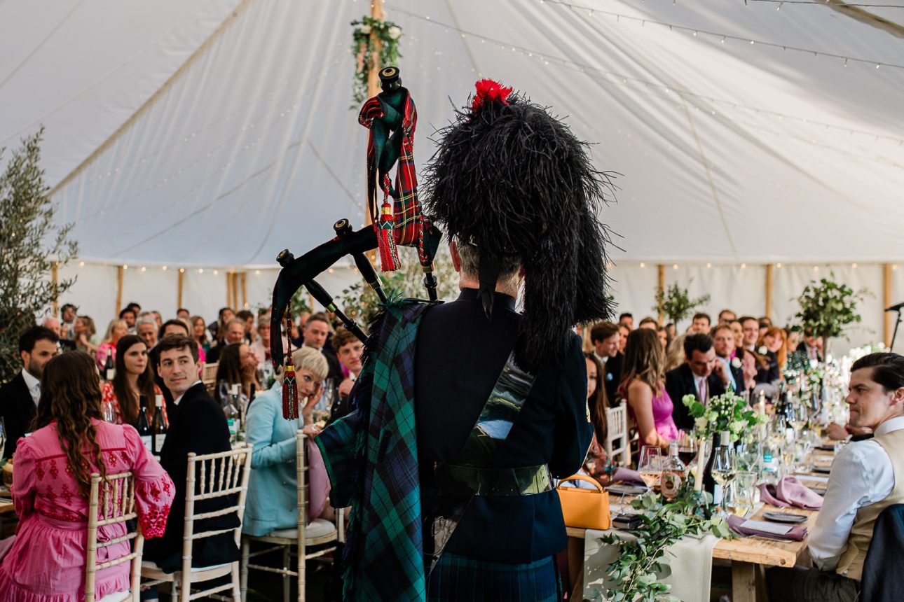 A bagpiper surprises wedding guests during a marquee reception near London.