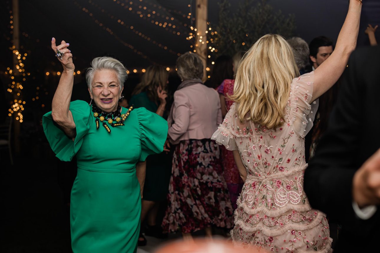 Two guests dance with energy, during an evening marquee reception.