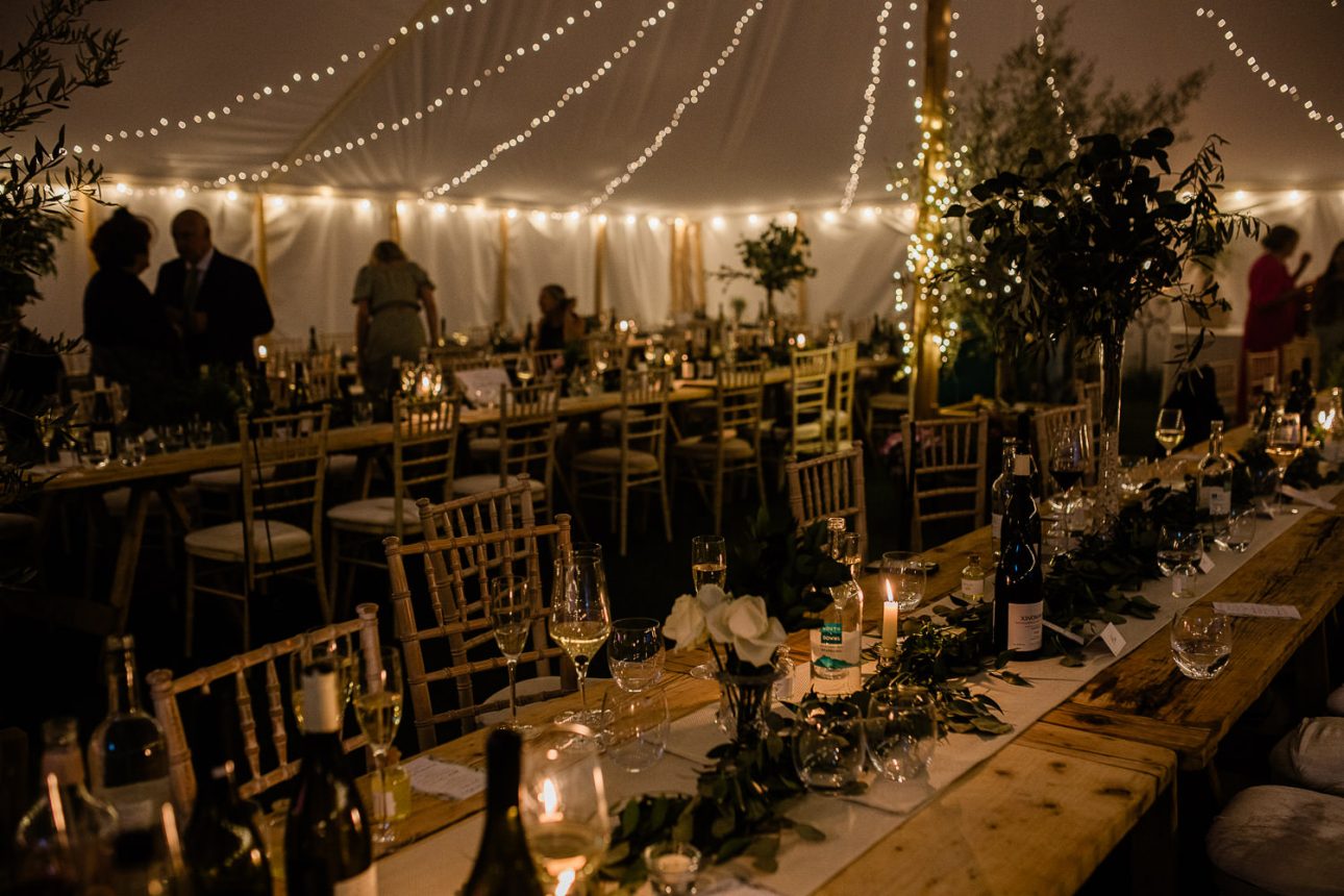 An atmospheric view of a marquee with candles and fairy lights, during the evening.