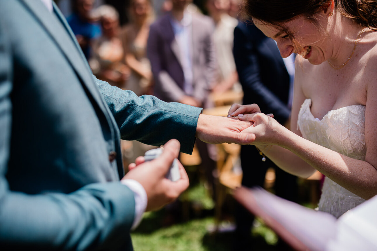 A bride laughs as she struggles to fit the ring on the grooms hand, during a civil ceremony at a French chateau.