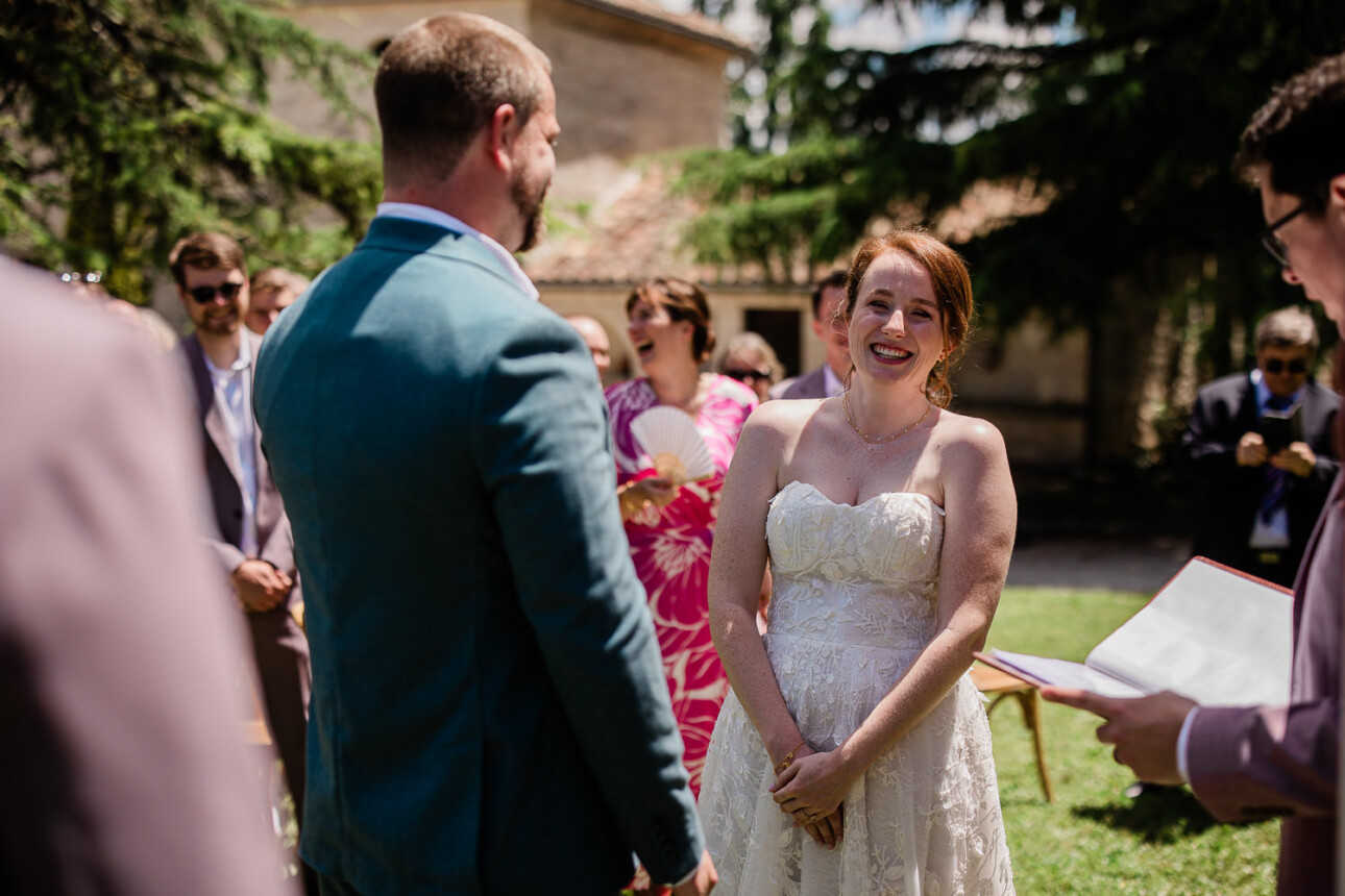A bride laughs at a joke as she stands at the altar with her soon to be husband.