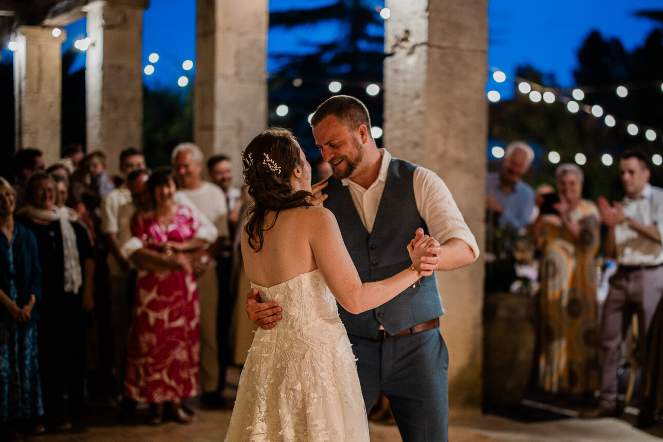 A groom and bride enjoy their romantic first dance at a french chateau, with their friends and family surrounding them.