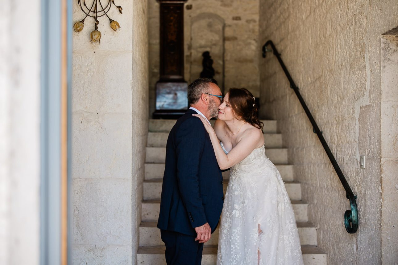 A french bride kisses her father on the cheek, during the first look.