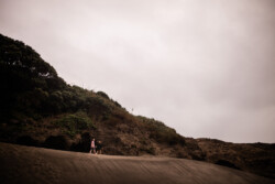 An artistic photography moment where partners explore Piha black sand beach in New Zealand
