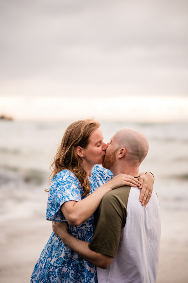 A young couple kiss, during a documentary photography photoshoot at a beach in New Zealand