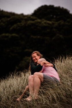 A couple share a hug on a windswept beach in NZ
